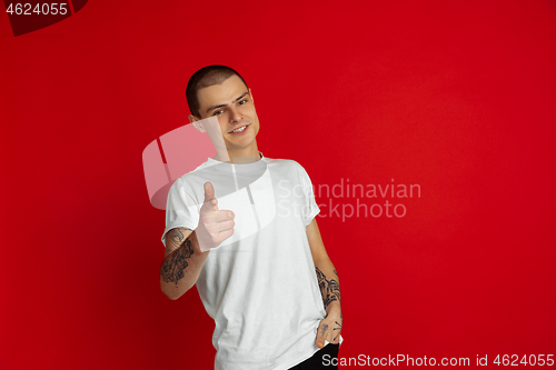 Image of Caucasian young man\'s portrait on red studio background, emotinal and expressive