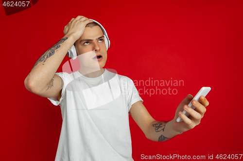 Image of Caucasian young man\'s portrait on red studio background with copyspace - emotional and expressive, angry and upset