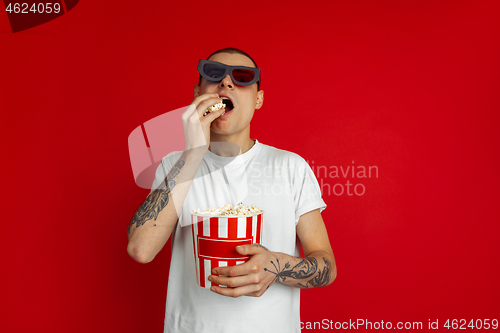 Image of Caucasian young man\'s portrait on red studio background, emotinal and expressive, cinema concept