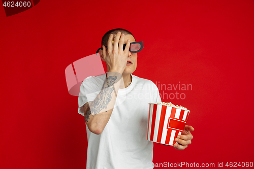 Image of Caucasian young man\'s portrait on red studio background, emotinal and expressive, cinema concept