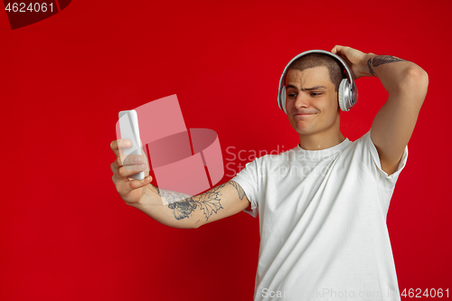 Image of Caucasian young man\'s portrait on red studio background with copyspace - emotional and expressive