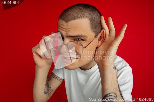 Image of Caucasian young man\'s portrait on red studio background, emotinal and expressive