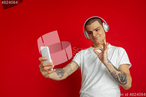 Image of Caucasian young man\'s portrait on red studio background with copyspace - emotional and expressive