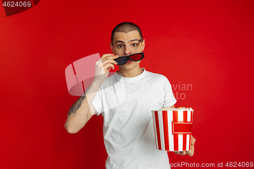 Image of Caucasian young man\'s portrait on red studio background, emotinal and expressive, cinema concept