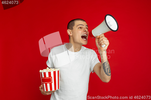 Image of Caucasian young man\'s portrait on red studio background, emotinal and expressive, cinema concept