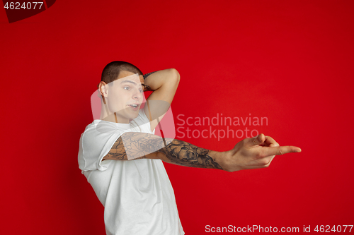 Image of Caucasian young man\'s portrait on red studio background, emotinal and expressive