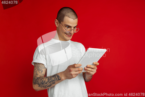 Image of Caucasian young man\'s portrait on red studio background with copyspace - emotional and expressive