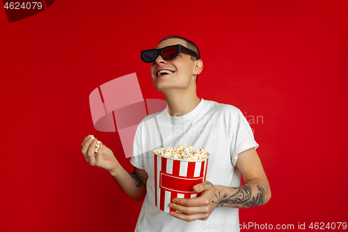 Image of Caucasian young man\'s portrait on red studio background, emotinal and expressive, cinema concept