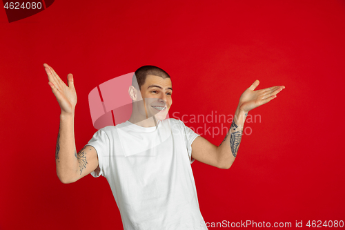 Image of Caucasian young man\'s portrait on red studio background, emotinal and expressive