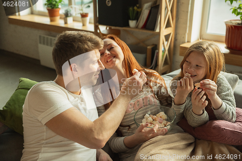 Image of Family spending nice time together at home, looks happy and cheerful, watching TV