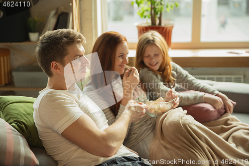 Image of Family spending nice time together at home, looks happy and cheerful, watching TV