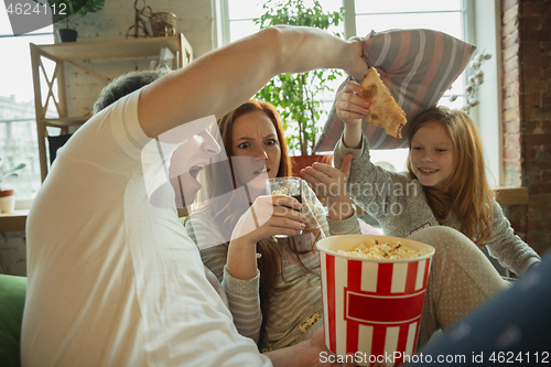 Image of Family spending nice time together at home, looks happy and cheerful, watching TV