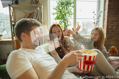 Image of Family spending nice time together at home, looks happy and cheerful, watching TV