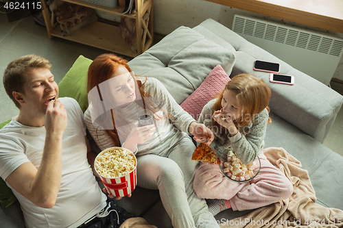 Image of Family spending nice time together at home, looks happy and cheerful, watching TV