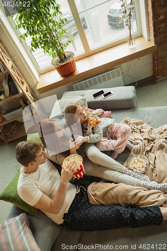 Image of Family spending nice time together at home, looks happy and cheerful, watching TV