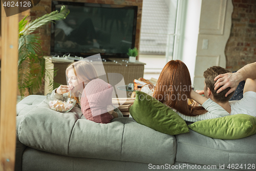Image of Family spending nice time together at home, looks happy and cheerful, watching TV