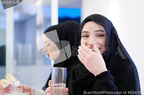 Image of Muslim family having Iftar dinner drinking water to break feast