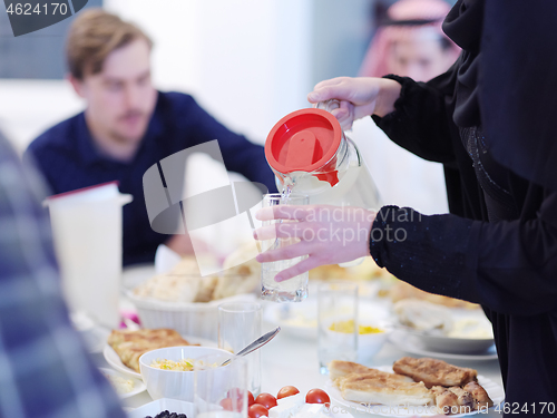 Image of Muslim family having Iftar dinner drinking water to break feast