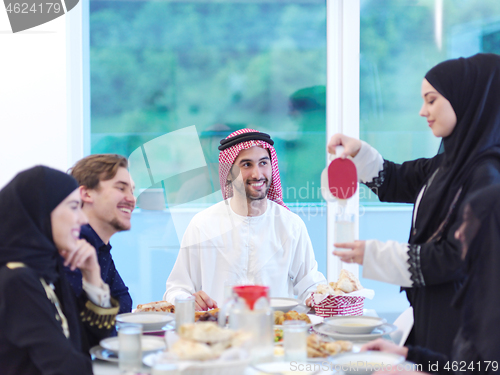 Image of Muslim family having Iftar dinner drinking water to break feast