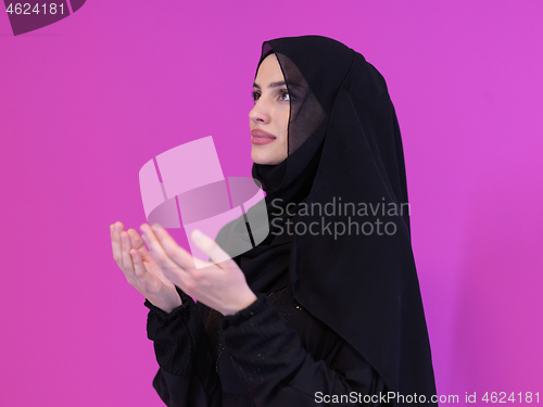 Image of muslim woman making traditional prayer to God isolated on pink