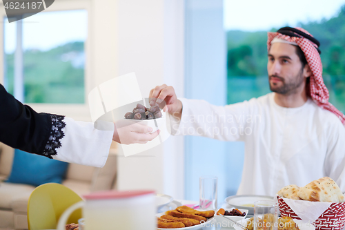 Image of Muslim family having Iftar dinner eating dates to break feast