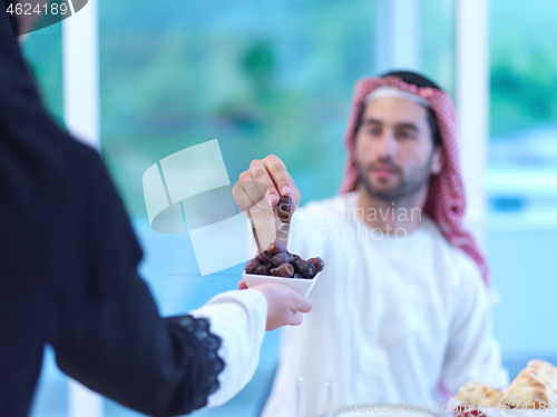 Image of Muslim family having Iftar dinner eating dates to break feast