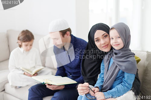 Image of muslim family reading Quran and praying at home