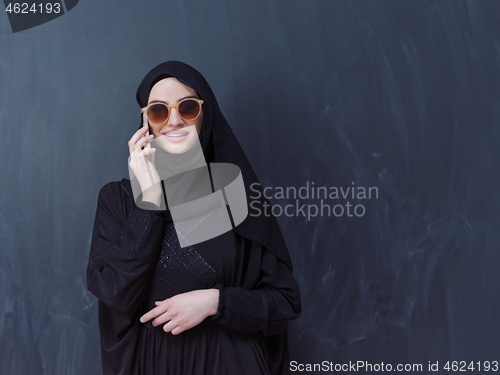 Image of young muslim woman wearing sunglasses using smartphone