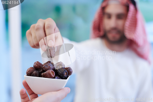 Image of Muslim family having Iftar dinner eating dates to break feast