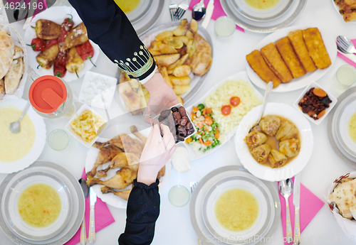 Image of Muslim family having Iftar dinner eating dates to break feast to