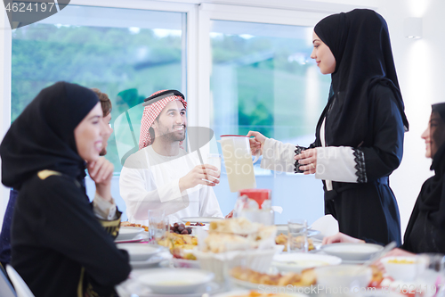 Image of Muslim family having Iftar dinner drinking water to break feast