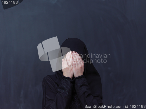 Image of muslim woman making traditional prayer to God in front of black 