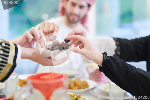 Image of Muslim family having Iftar dinner eating dates to break feast