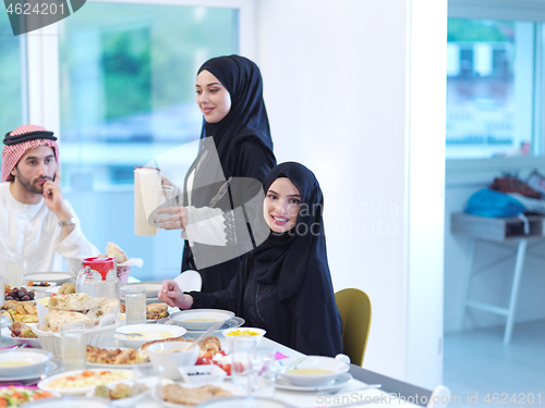 Image of Muslim family having Iftar dinner drinking water to break feast