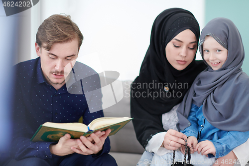 Image of muslim family reading Quran and praying at home