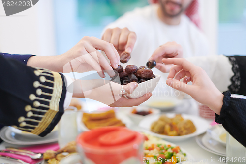 Image of Muslim family having Iftar dinner eating dates to break feast