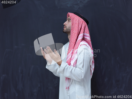 Image of arabian man making traditional prayer to God, keeps hands in pra