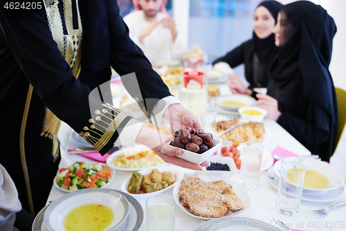 Image of Muslim family having Iftar dinner eating dates to break feast