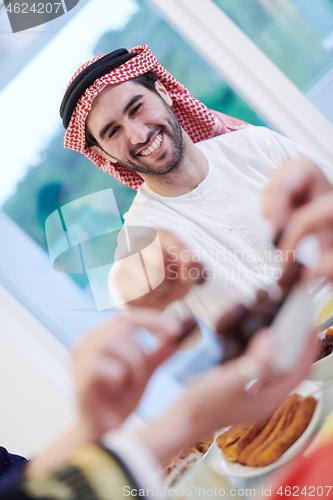 Image of Muslim family having Iftar dinner eating dates to break feast