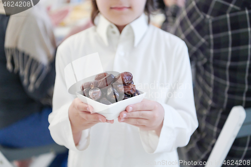 Image of little muslim boy holding a plate full of sweet dates