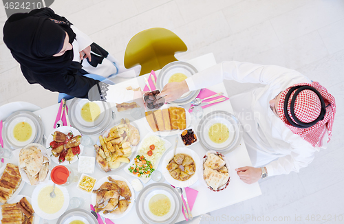 Image of Muslim family having Iftar dinner eating dates to break feast to