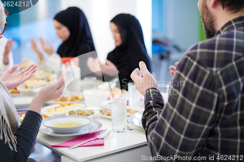 Image of traditional muslim family praying before iftar dinner