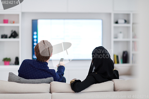 Image of young muslim couple watching TV together