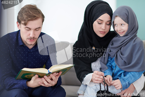 Image of muslim family reading Quran and praying at home