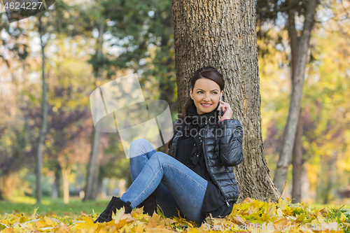 Image of Woman with a Mobile in a Forest in the Autumn