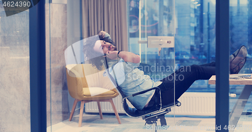 Image of businessman sitting with legs on desk