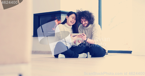 Image of Young Couple using digital tablet on the floor