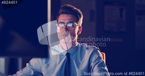 Image of man working on computer in dark office