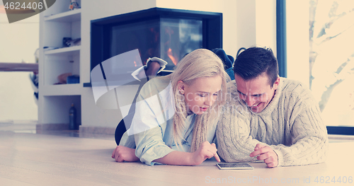 Image of Young Couple using digital tablet on the floor