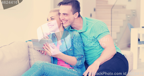 Image of couple relaxing at  home with tablet computers